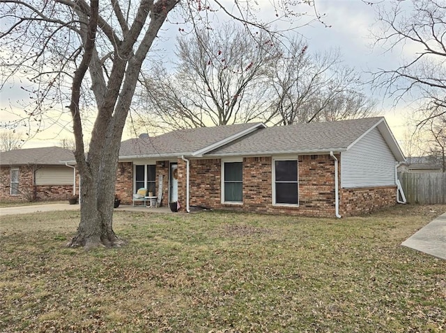 ranch-style house with a front yard, a patio area, brick siding, and roof with shingles