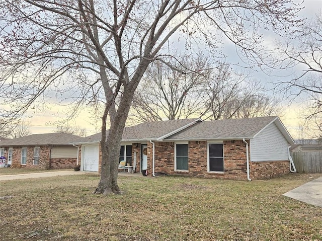 ranch-style home featuring a garage, brick siding, concrete driveway, roof with shingles, and a front yard