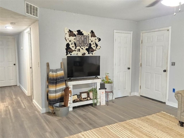 living room with baseboards, visible vents, ceiling fan, and wood finished floors