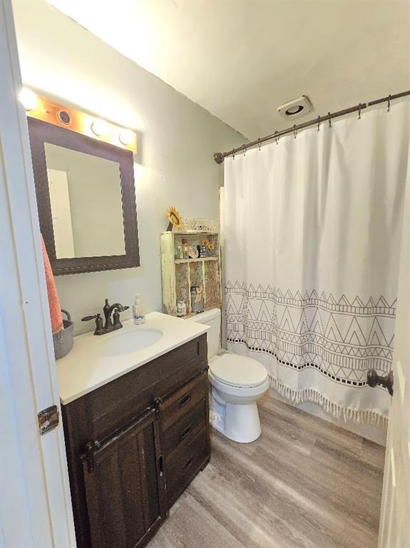 full bathroom featuring curtained shower, vanity, toilet, and wood finished floors