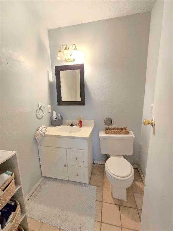 half bathroom featuring tile patterned flooring, baseboards, vanity, and toilet