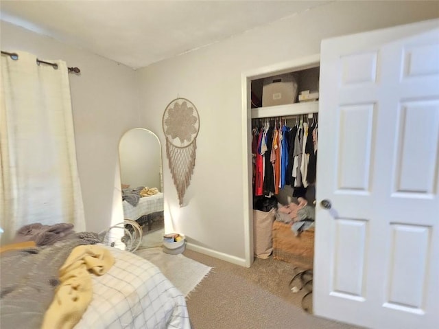 carpeted bedroom with a closet and baseboards