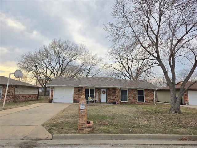 ranch-style home with driveway, a garage, a shingled roof, a front lawn, and brick siding