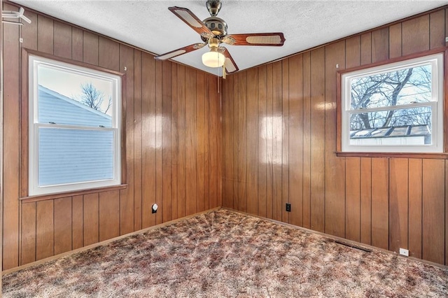 unfurnished room featuring carpet flooring, wood walls, and ceiling fan