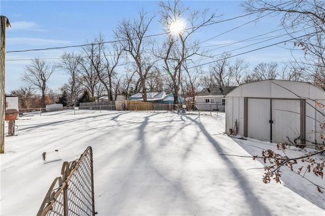 yard layered in snow with an outbuilding, a fenced backyard, and a shed