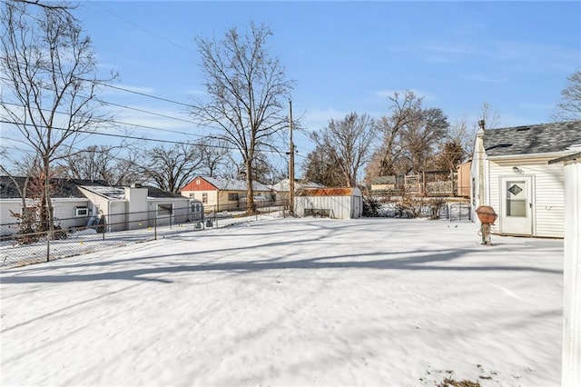 yard layered in snow featuring a residential view and fence