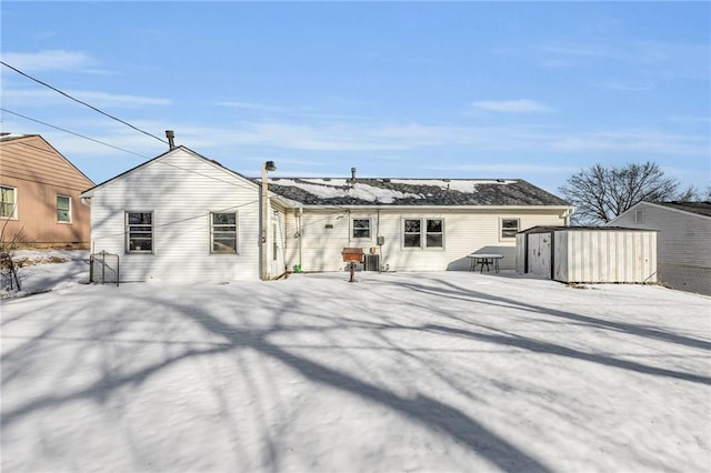 snow covered property with a storage shed and an outbuilding