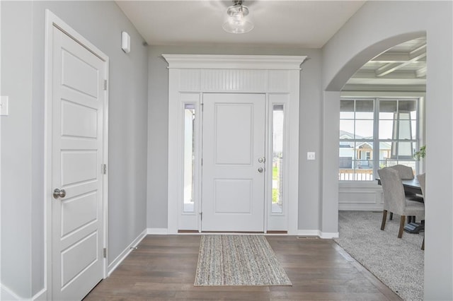 foyer entrance featuring dark wood-type flooring, coffered ceiling, and beamed ceiling