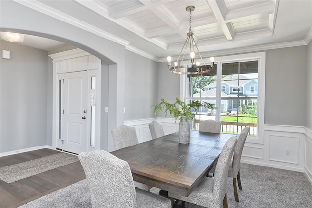 carpeted dining area with an inviting chandelier, coffered ceiling, ornamental molding, and beamed ceiling