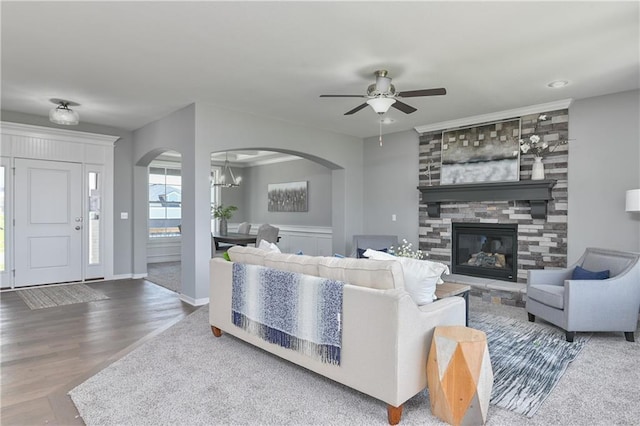 living room featuring wood-type flooring, a fireplace, and ceiling fan with notable chandelier