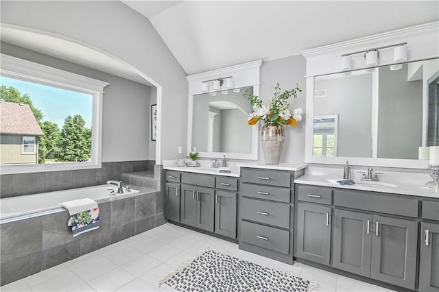 bathroom featuring vanity, vaulted ceiling, and tiled bath