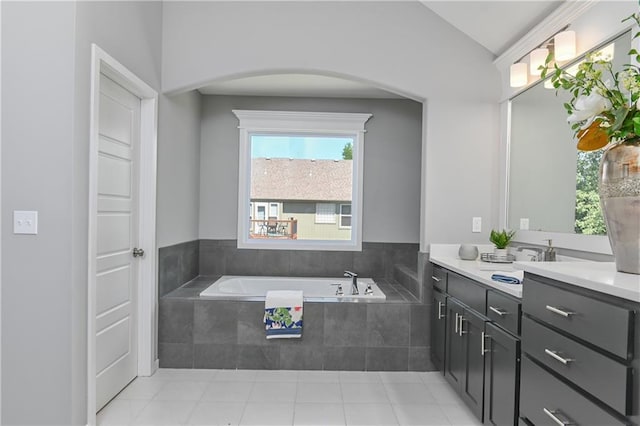 bathroom featuring lofted ceiling, vanity, tiled bath, and tile patterned floors