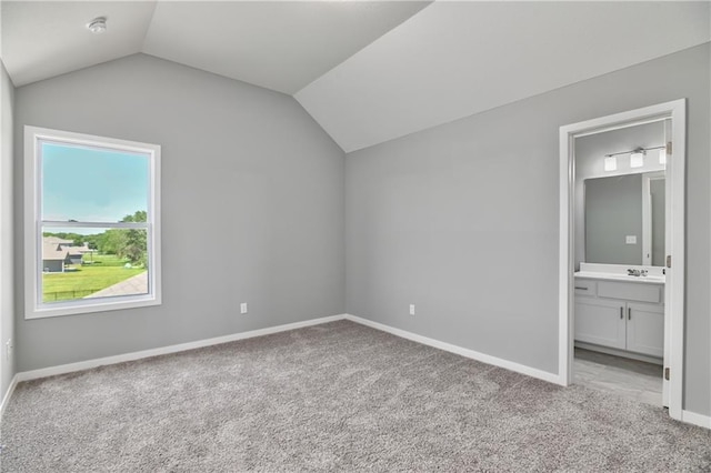 unfurnished bedroom featuring lofted ceiling, ensuite bathroom, and light carpet