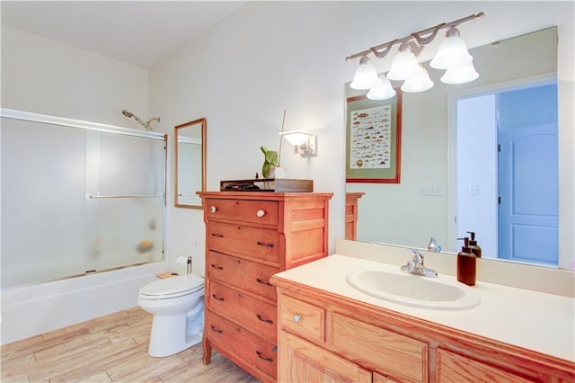 full bathroom featuring bath / shower combo with glass door, vanity, wood finished floors, and toilet