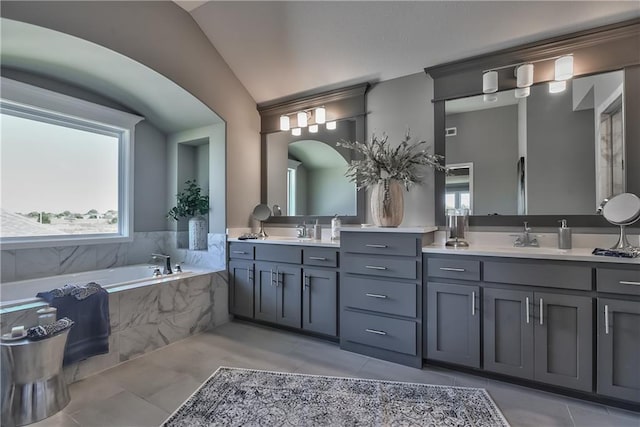 bathroom with tiled tub, vanity, a wealth of natural light, and tile patterned floors