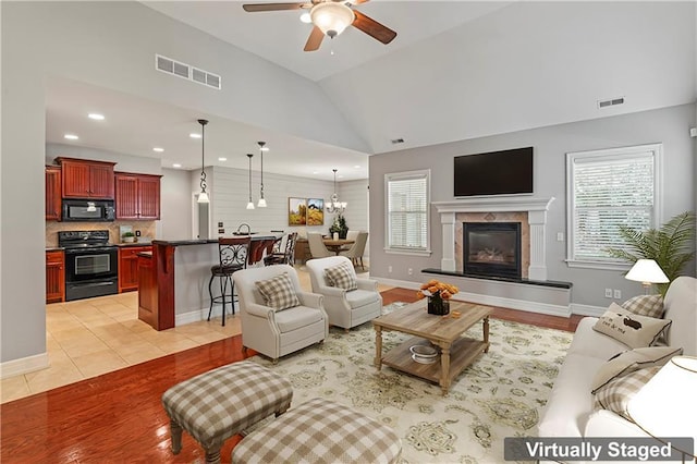 tiled living room with lofted ceiling, ceiling fan with notable chandelier, and plenty of natural light