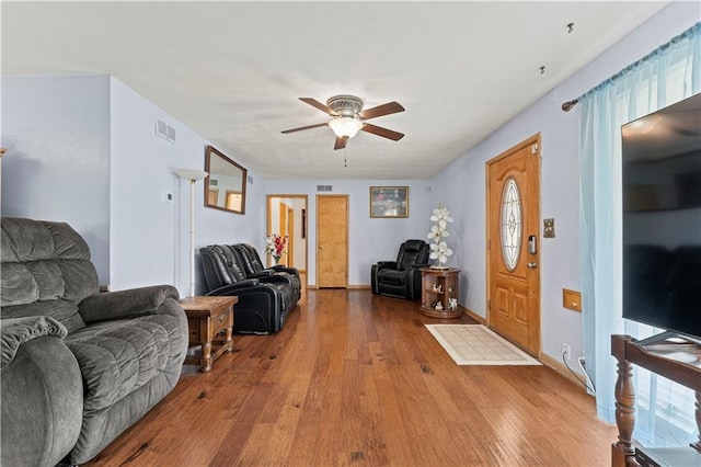 living area with light wood finished floors, ceiling fan, visible vents, and baseboards