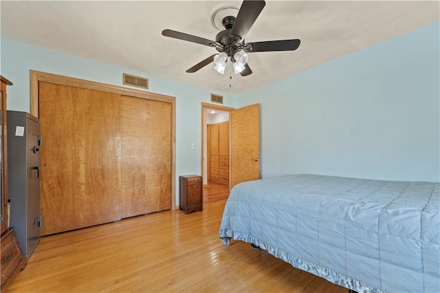 bedroom featuring light wood-style flooring, a closet, visible vents, and a ceiling fan