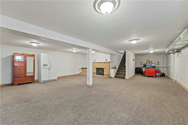 finished basement with carpet, white fridge with ice dispenser, stairway, and a fireplace