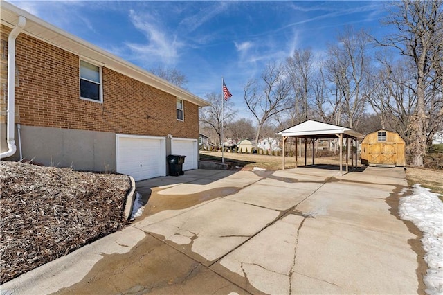 view of side of property featuring an attached garage, a gazebo, concrete driveway, and brick siding