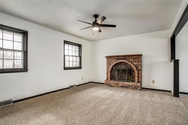 unfurnished living room with ceiling fan, carpet, a brick fireplace, and a textured ceiling