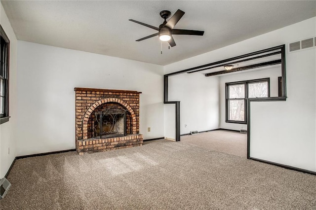 unfurnished living room featuring ceiling fan, carpet flooring, and a brick fireplace