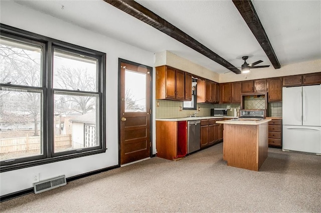 kitchen with tasteful backsplash, a wealth of natural light, a kitchen island, and appliances with stainless steel finishes