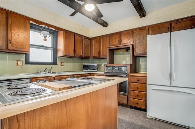 kitchen featuring black oven, tasteful backsplash, sink, white fridge, and ceiling fan