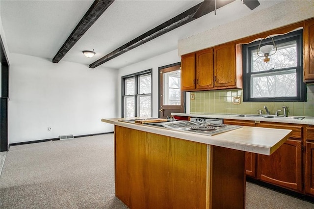 kitchen with sink, a kitchen island, a wealth of natural light, beam ceiling, and backsplash