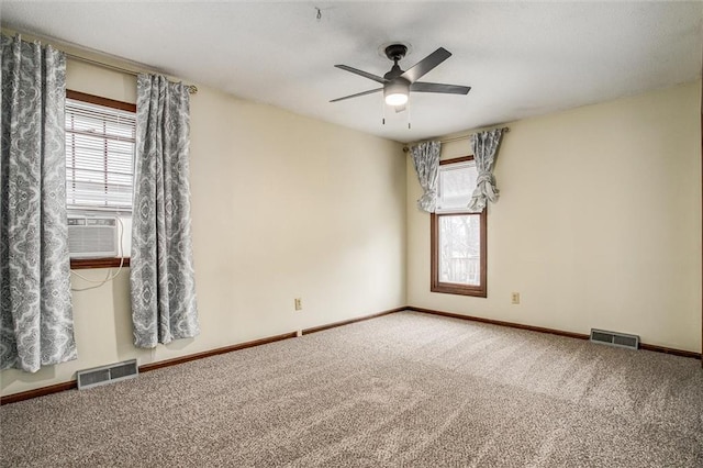 carpeted spare room featuring cooling unit, ceiling fan, and a wealth of natural light