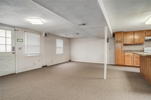 kitchen featuring light carpet, decorative backsplash, and a textured ceiling