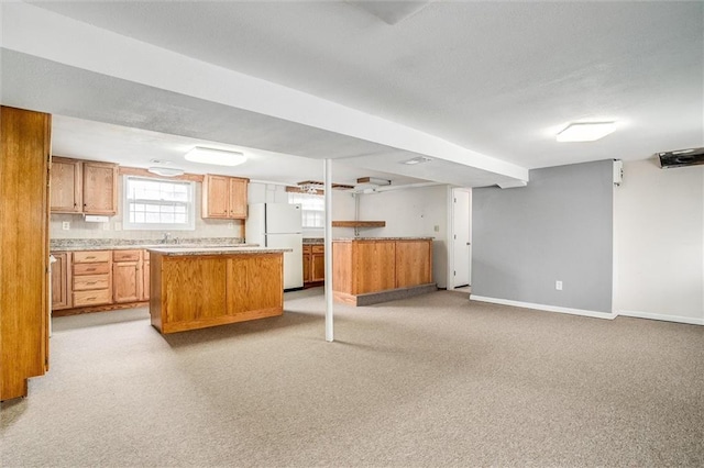 kitchen with a kitchen island, white fridge, and light carpet