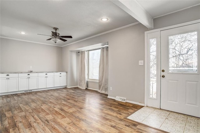 entrance foyer with light wood-style floors, a healthy amount of sunlight, and ornamental molding