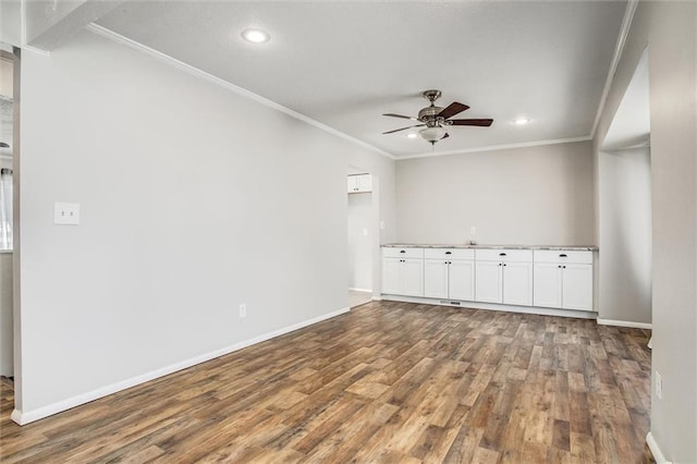 unfurnished room with ceiling fan, wood finished floors, baseboards, and ornamental molding