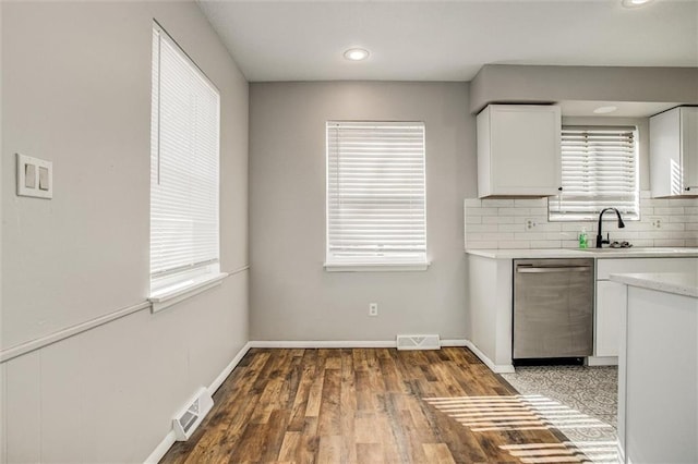 kitchen with visible vents, decorative backsplash, light countertops, white cabinets, and stainless steel dishwasher