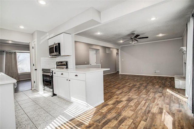 kitchen featuring ceiling fan, light countertops, appliances with stainless steel finishes, light wood-style floors, and white cabinets