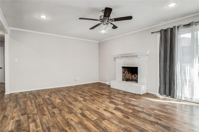 unfurnished living room with a brick fireplace, a textured ceiling, crown molding, and wood finished floors