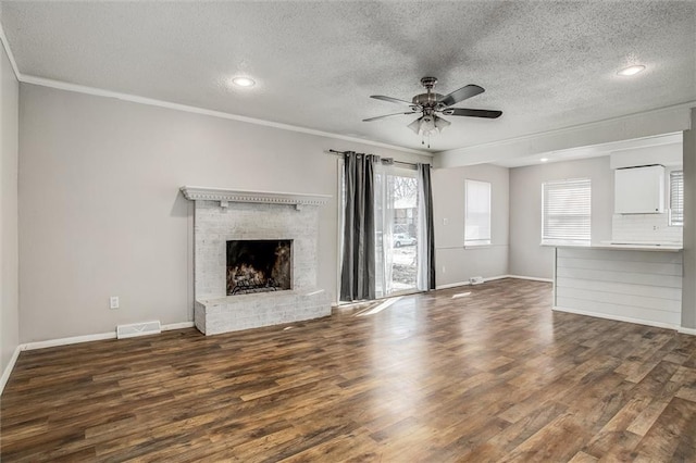 unfurnished living room with wood finished floors, visible vents, a ceiling fan, a fireplace, and crown molding