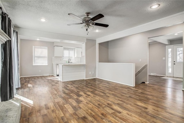 unfurnished living room with wood finished floors, baseboards, and a sink