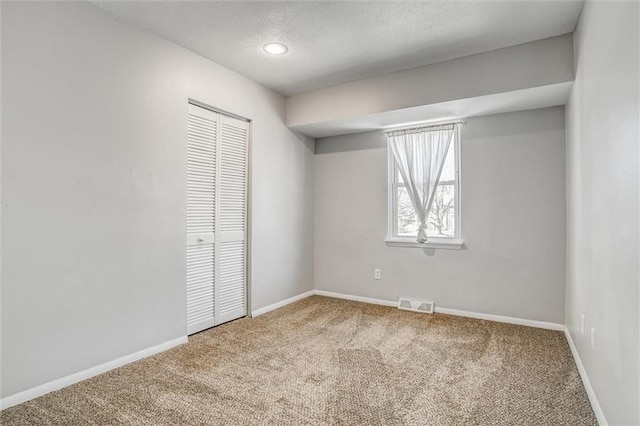 unfurnished bedroom with visible vents, baseboards, carpet, and a closet