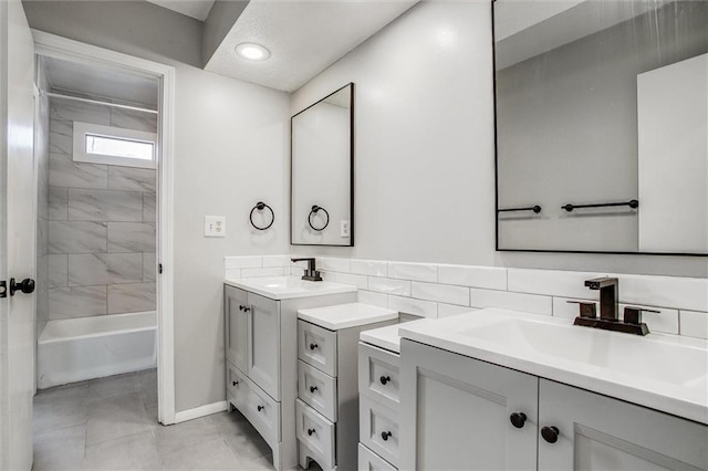 bathroom featuring two vanities, bathing tub / shower combination, and a sink