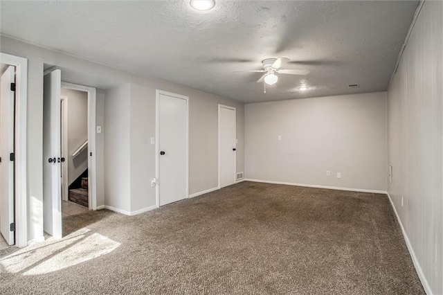 unfurnished bedroom featuring a ceiling fan, carpet, baseboards, a textured ceiling, and two closets