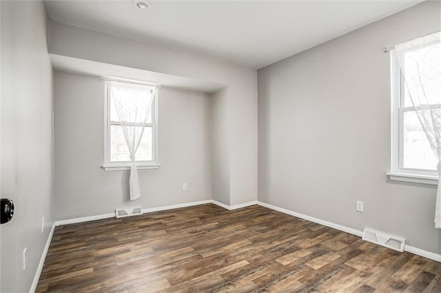 spare room with visible vents, baseboards, and wood finished floors