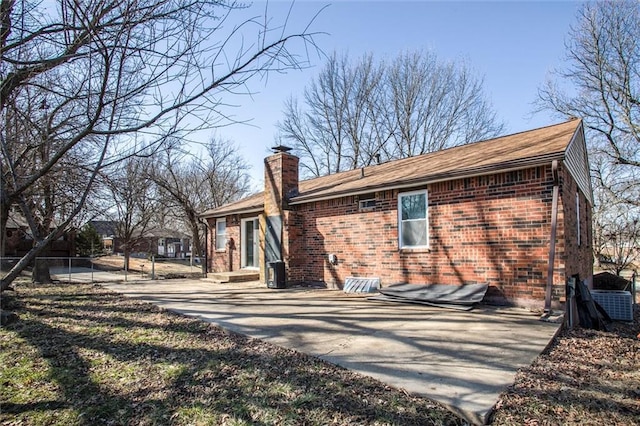 rear view of property featuring brick siding and a chimney