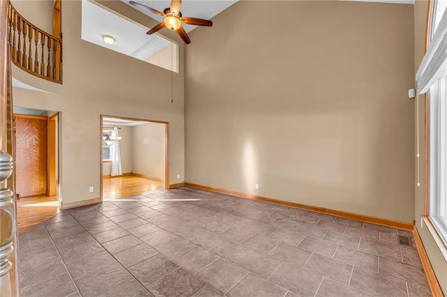 unfurnished living room with ceiling fan with notable chandelier and a towering ceiling