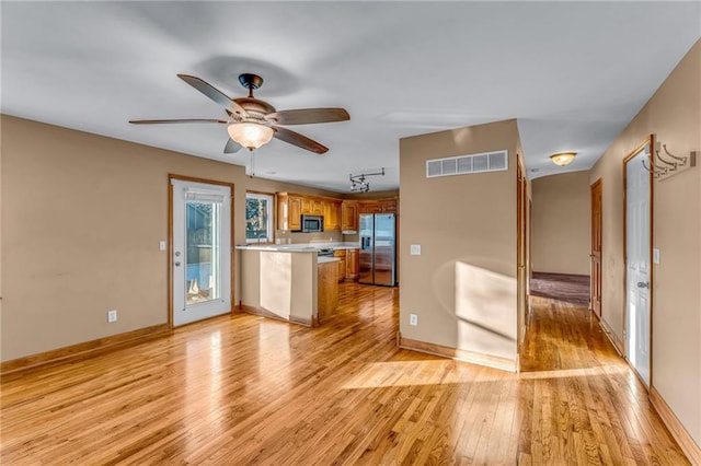 kitchen with ceiling fan, stainless steel appliances, kitchen peninsula, and light wood-type flooring