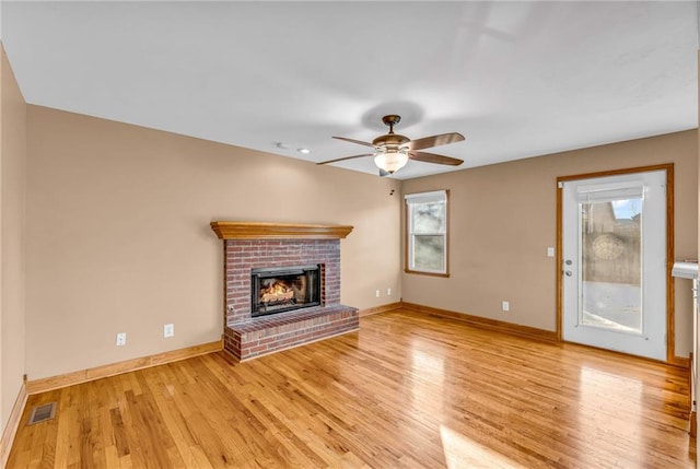 unfurnished living room featuring a brick fireplace, ceiling fan, and light hardwood / wood-style flooring