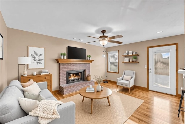 living room featuring a fireplace, light hardwood / wood-style flooring, and ceiling fan