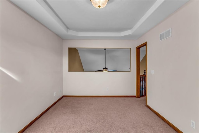 unfurnished room featuring light colored carpet and a tray ceiling