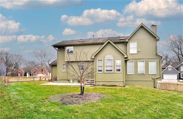 rear view of house with a patio, a yard, a chimney, and fence